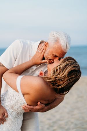 Intimate beach wedding moment with couple sharing passionate embrace.