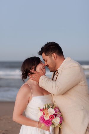 A romantic beach wedding moment with a couple embracing by the ocean waves.