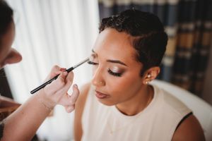 Makeup artist applies wedding day cosmetics during bridal preparation.