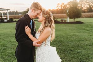 A romantic sunset moment on a lawn between newlyweds in formal wedding attire.