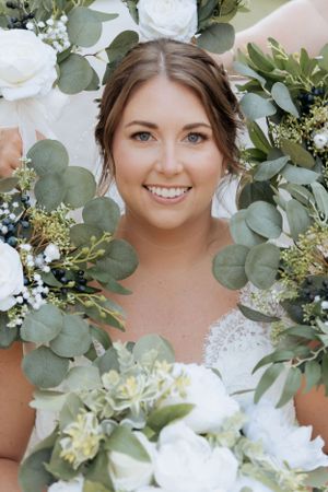 Bridal portrait framed by white roses and eucalyptus greenery wreath.