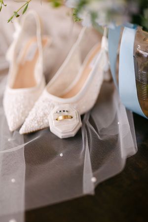 White wedding heels with delicate pearl details and a sheer veil in soft focus create an elegant bridal still life.