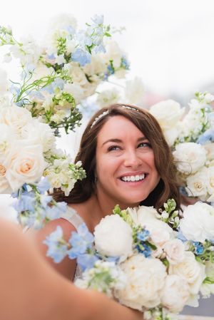 A bridal portrait surrounded by delicate white roses and light blue flowers in a soft, dreamy composition.