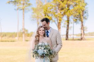 A romantic couple embraces in a sunlit field with golden trees and soft autumn lighting.
