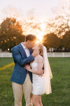 A romantic sunset engagement photo session in a grassy field with white fences and golden light.