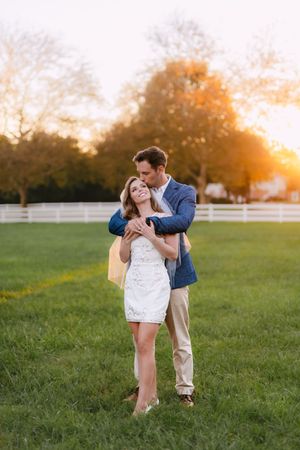 A couple shares intimate moments in a sunlit field during their wedding photoshoot.