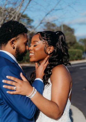 Intimate moment between newlyweds in blue suit and white lace gown.