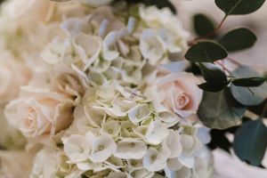 Delicate arrangement of white hydrangeas and blush roses with eucalyptus leaves.
