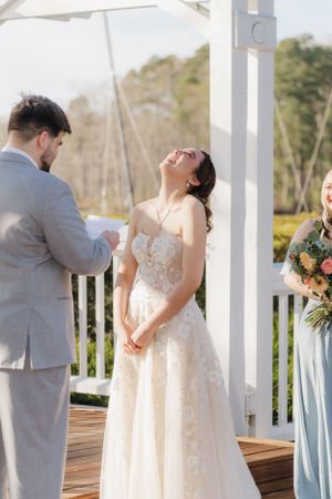 Joyful wedding ceremony moment on wooden deck with white pergola.