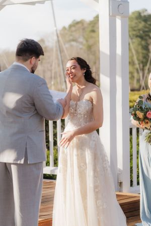 Sweet candid moment during wedding ceremony under white pergola.