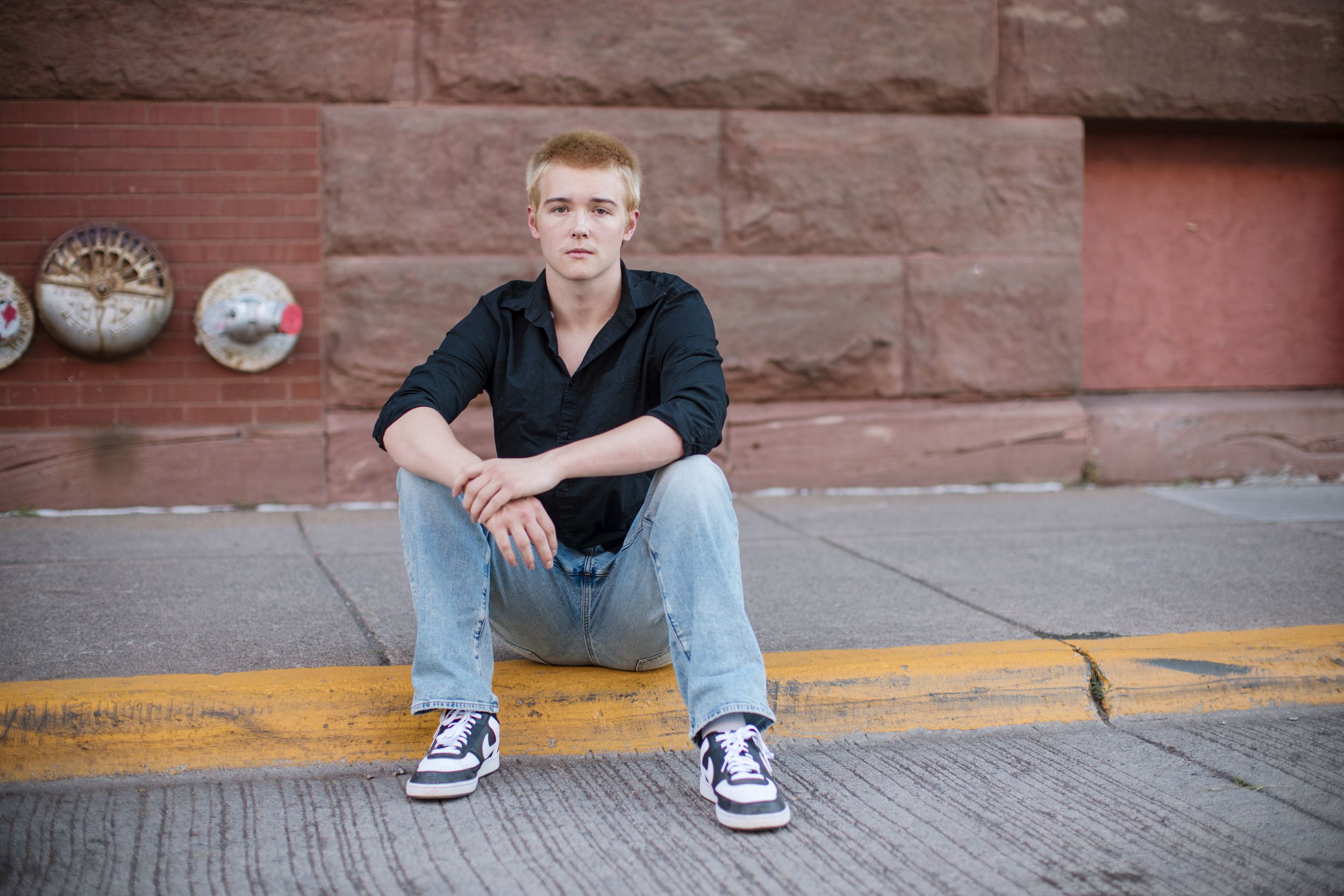 A casual photo series against a brick wall showing relaxed poses on concrete steps in urban setting.