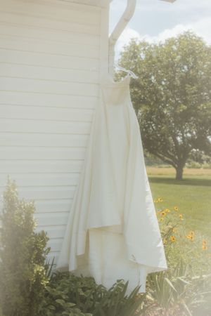 White linens drying on a clothesline against a sunny rural backdrop with sunflowers.