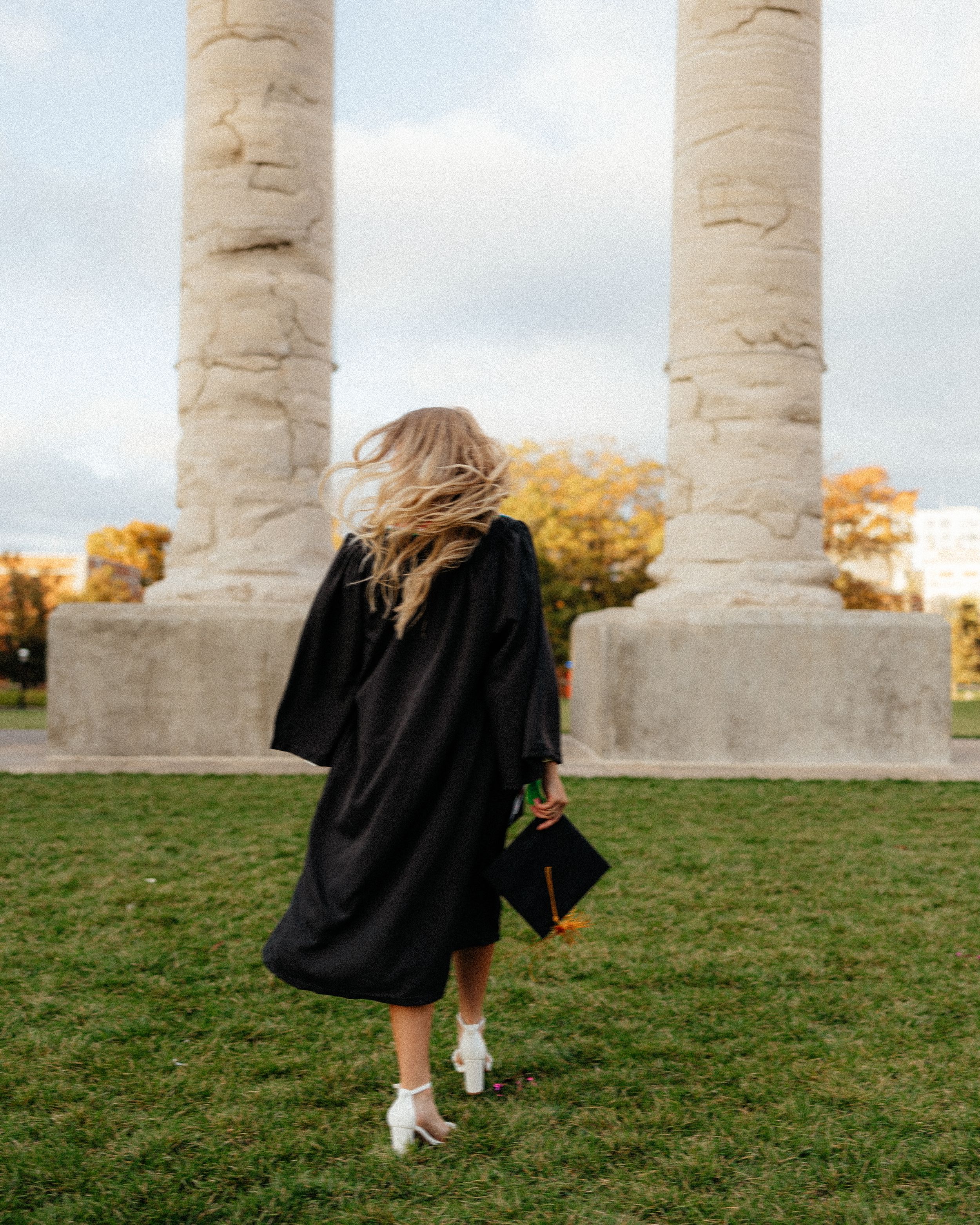 Walking sequence near white stone columns on grassy hill during autumn.