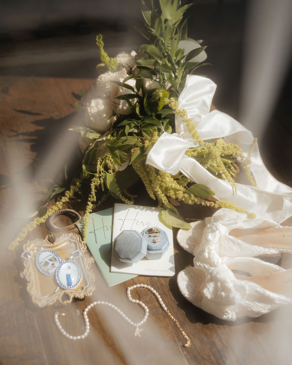 Wedding details flatlay with pearls, flowers and delicate accessories in soft lighting.