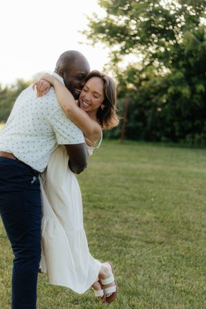 Joyful embrace sequence on grassy field during golden hour.