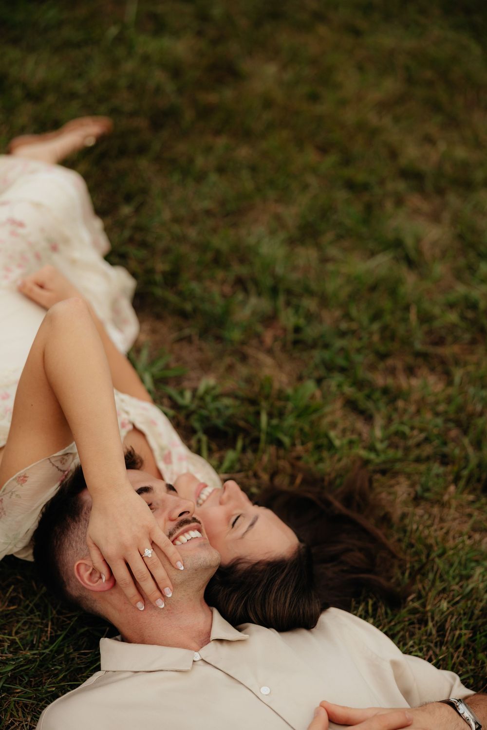 Couple lying together on grass sharing intimate moment outdoors.