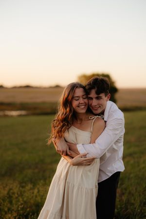 Romantic couple portraits in a field during golden hour sunset.