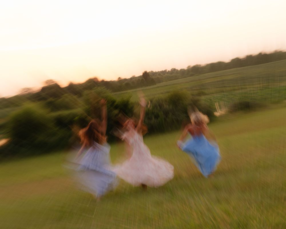 Motion-blur photos of people running and spinning in a grassy field at dusk.