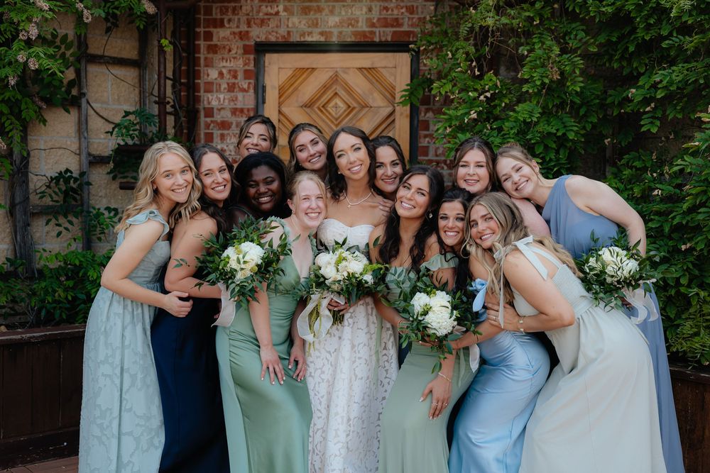 Wedding party in coordinated pastel dresses posing together outdoors.