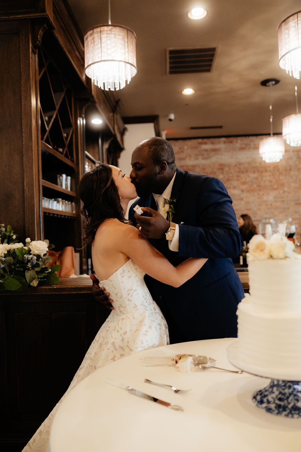 Romantic moment between newlyweds sharing cake at their wedding reception.