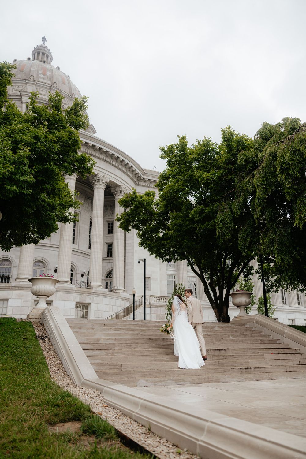Grand stone building with classical architecture and sweeping steps creates dramatic wedding backdrop.