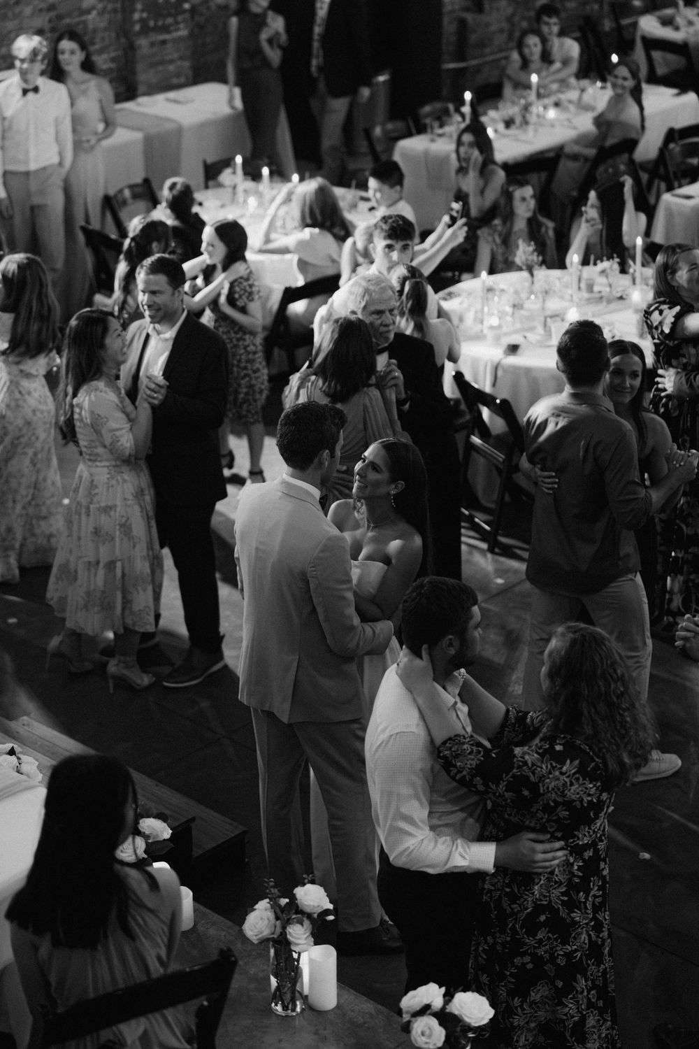 Wedding guests dancing and celebrating at a reception with black and white photography.