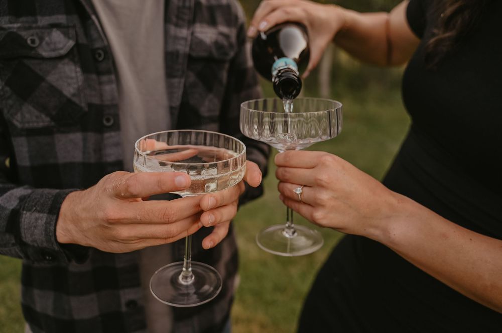 Hands pouring champagne into elegant glasses during an outdoor celebration.