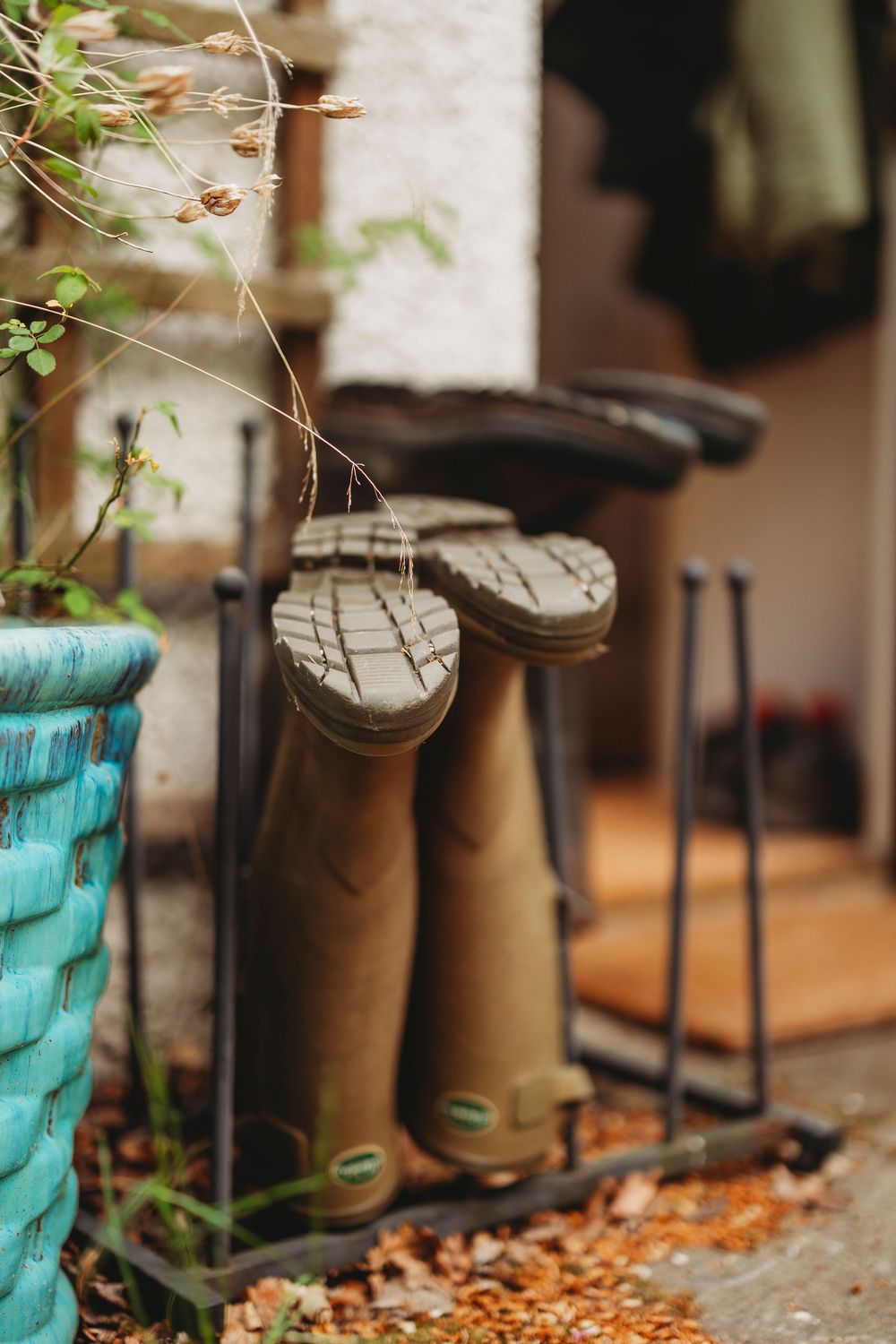 A row of vintage lanterns with turquoise glass bases arranged on a rustic wooden surface with autumn leaves.