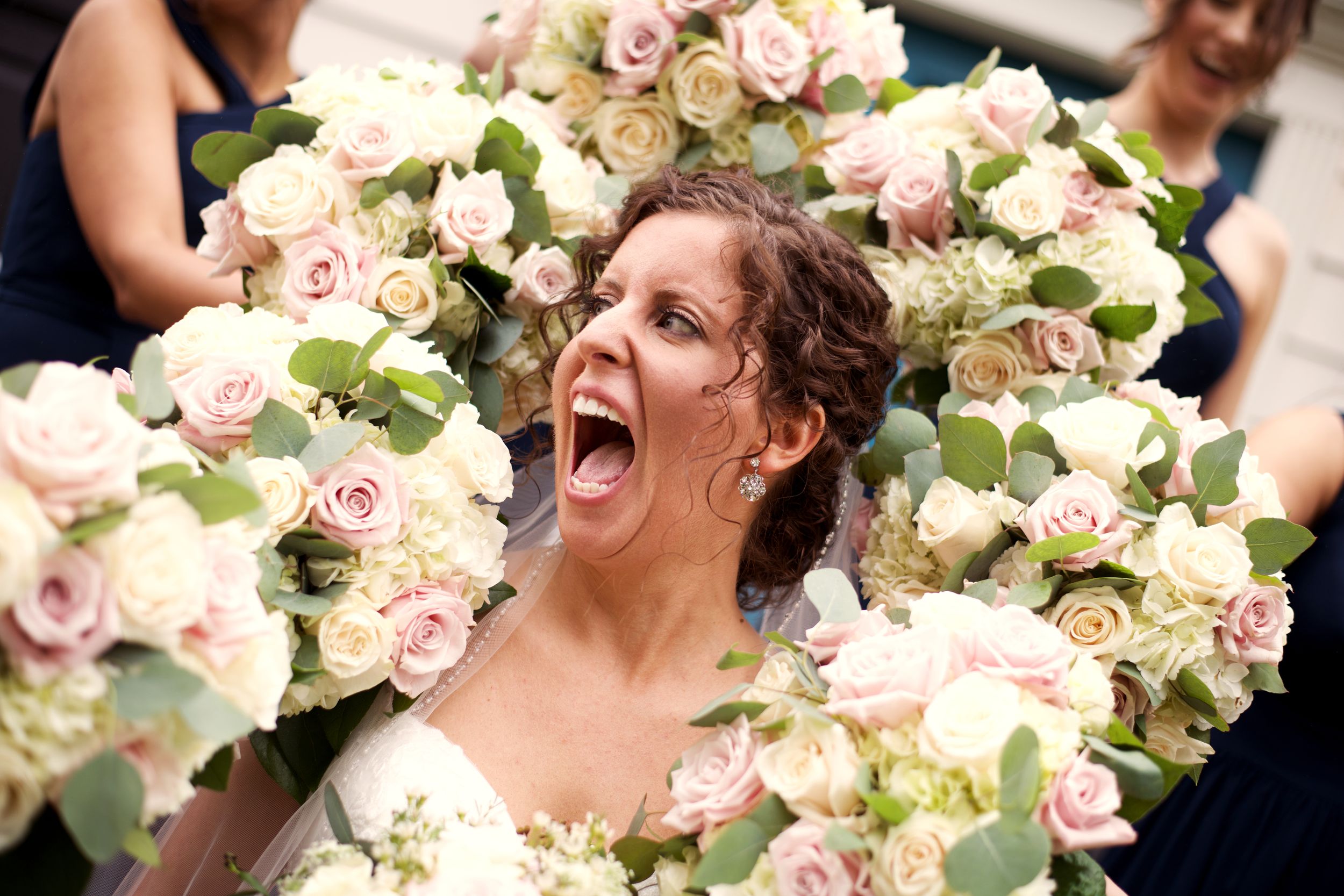 bride with flowers/bouquets; bridal party; bridesmaids; laughing