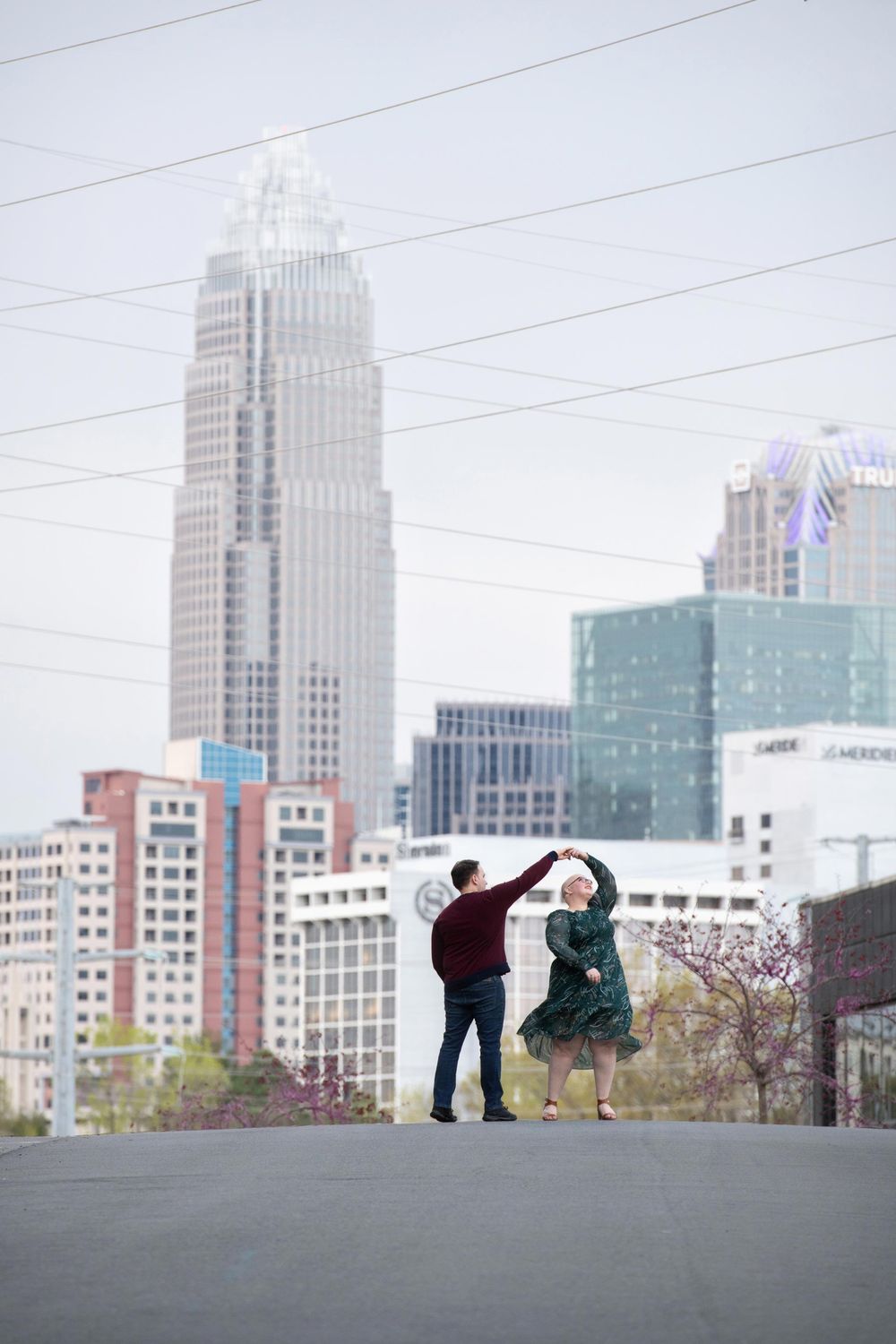 Two figures dancing together with Charlotte city skyline and skyscrapers in the background.
