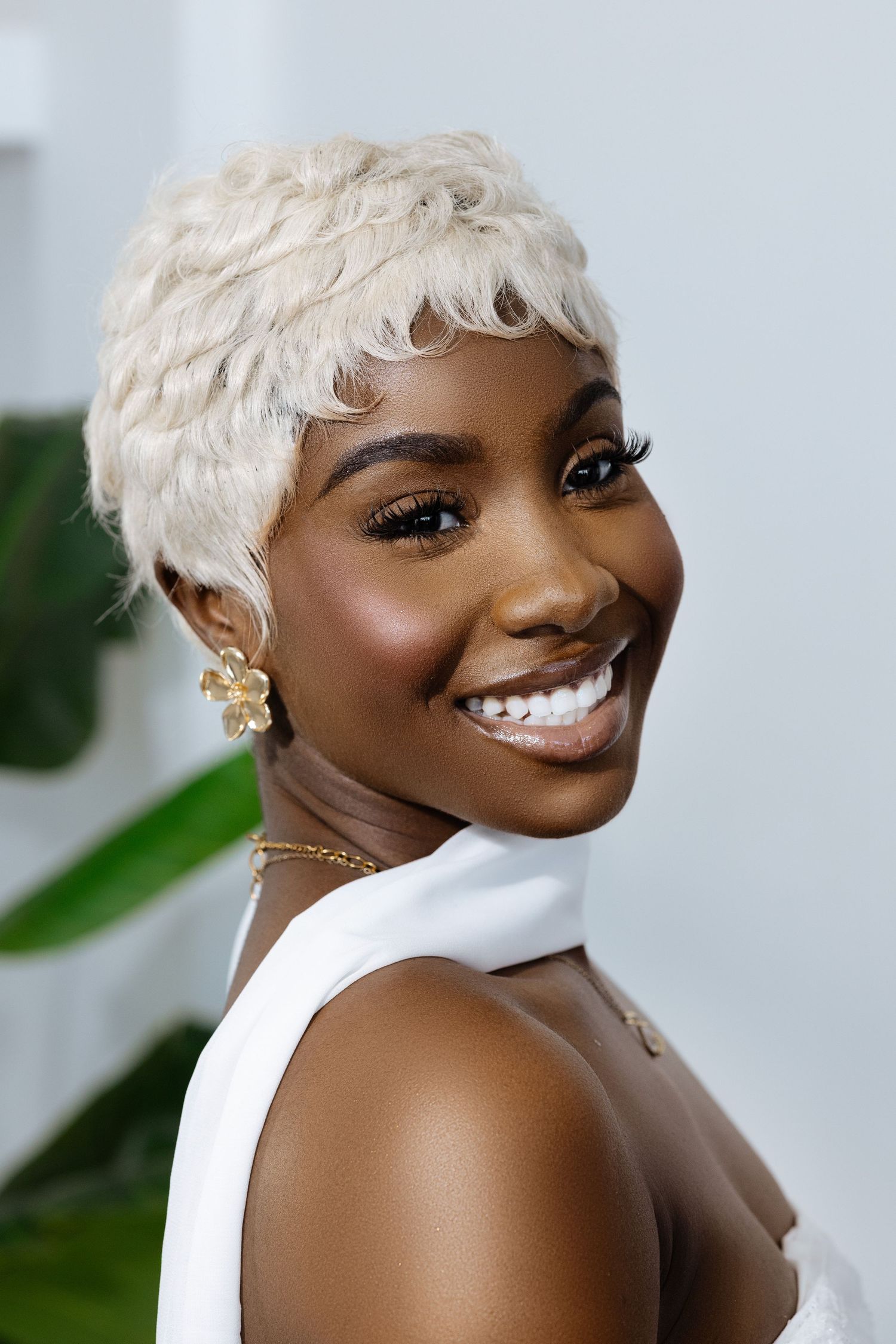 Side profile portrait showcasing platinum blonde short hairstyle and delicate jewelry.