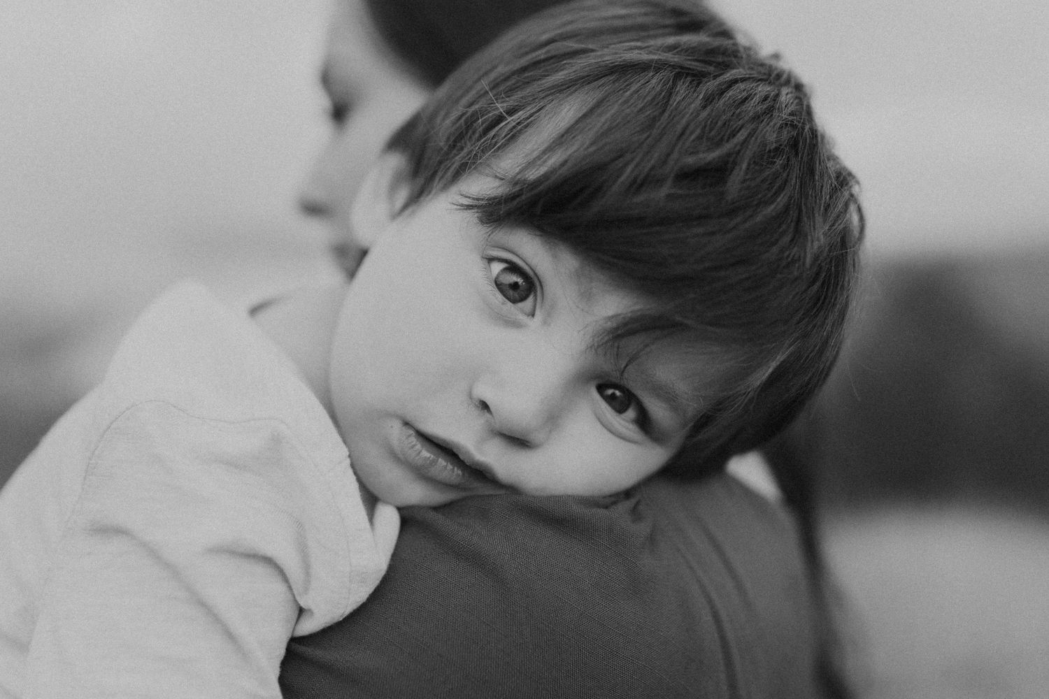 An artistic black and white close-up portrait capturing an intimate parental moment.