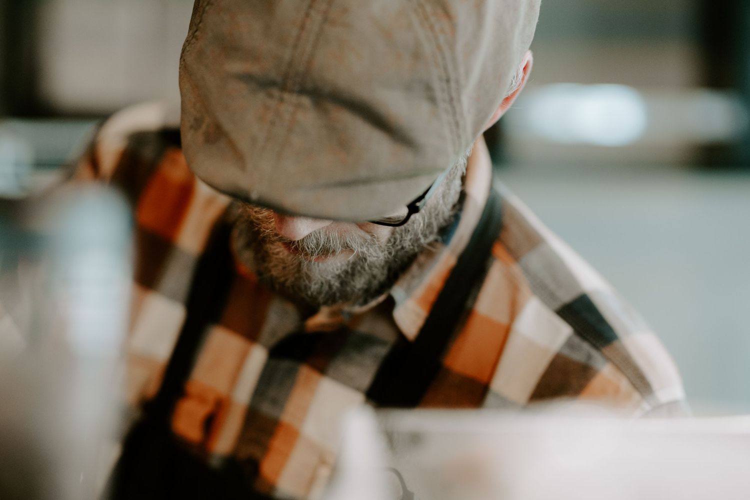 Close-up profile view of person wearing plaid flannel and beanie looking downward.