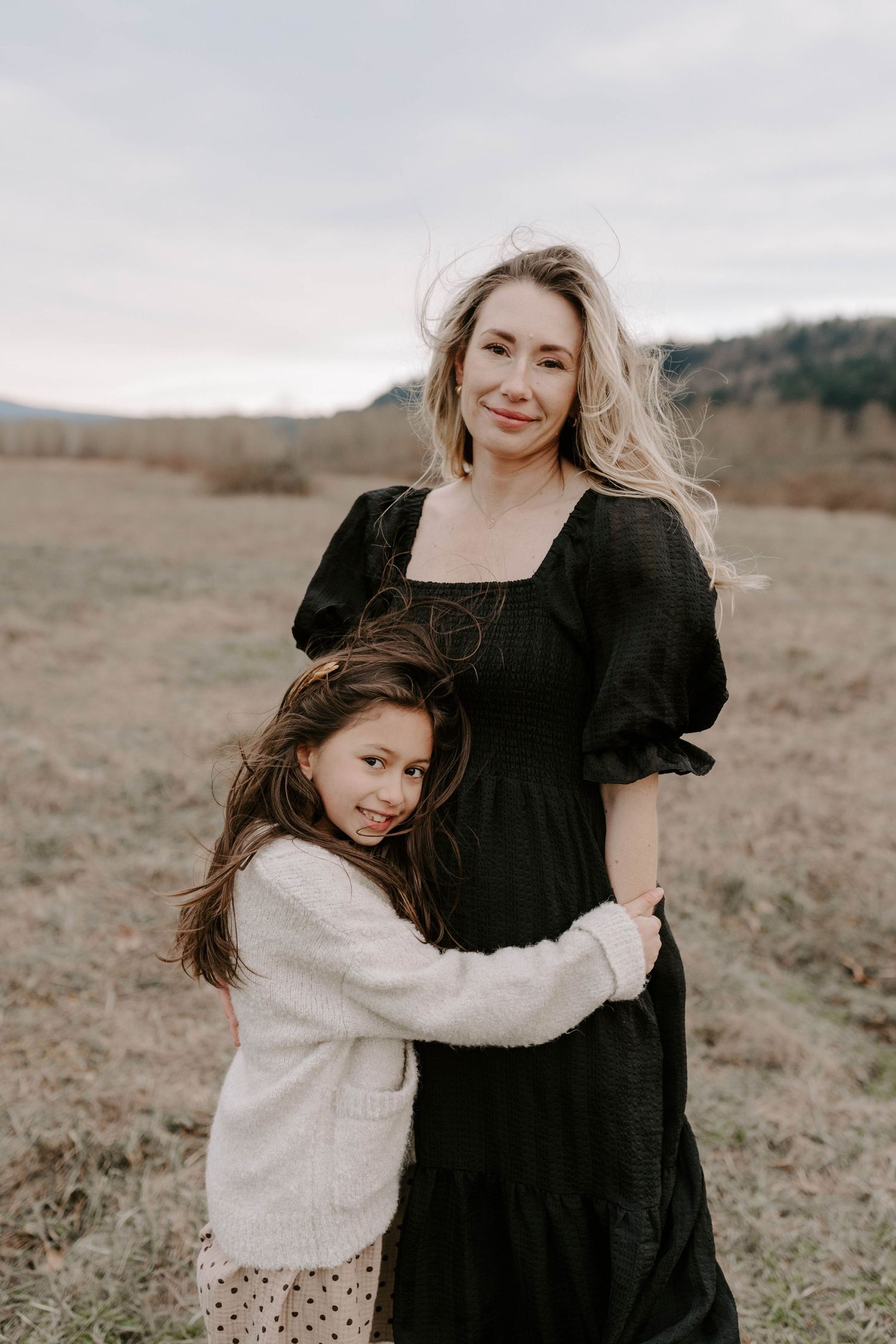 A tender mother-child moment captured in a field with muted earth tones and natural lighting.