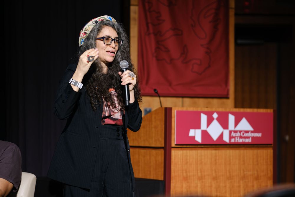 Speaker presenting with microphone at Harvard Arab Conference event.