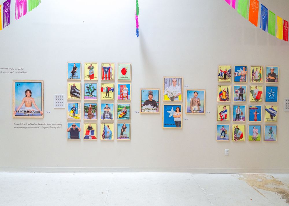 Colorful children's artwork and photographs displayed on a white wall with festive banners hanging above.