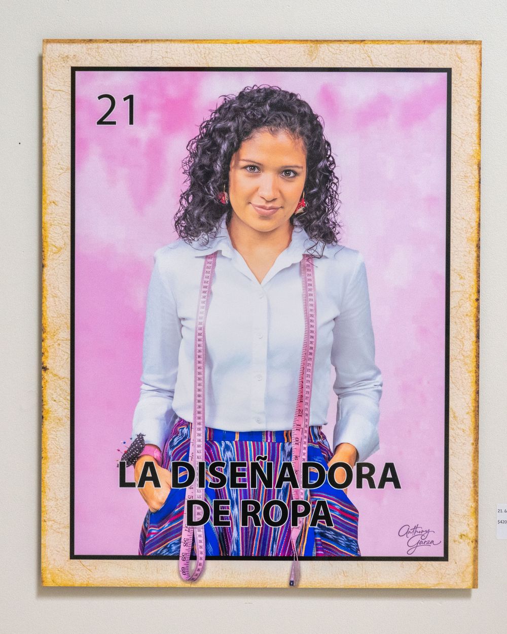 Fashion designer wearing light blue shirt and pink suspenders stands against pink background in professional headshot series.
