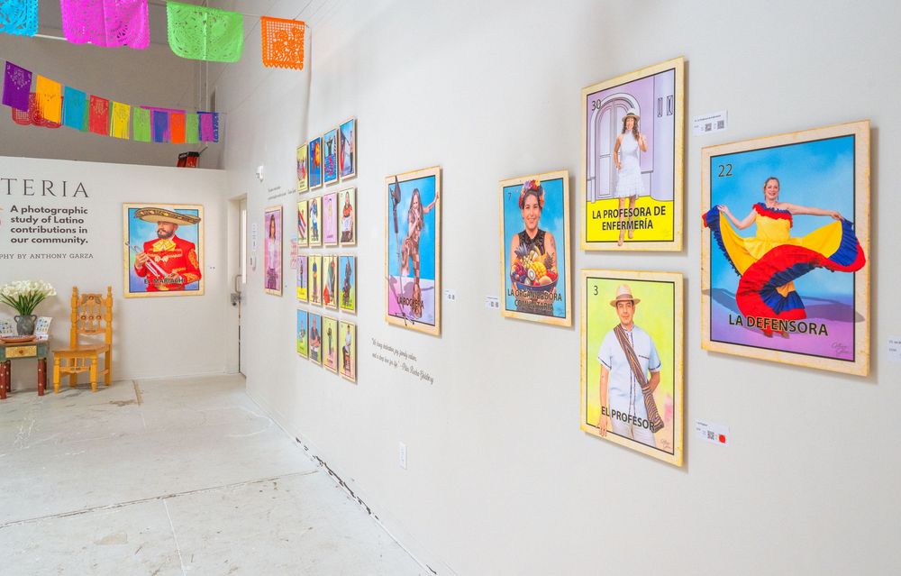 Art gallery interior with white walls displaying colorful framed artwork and illustrations in a clean, modern exhibition space.