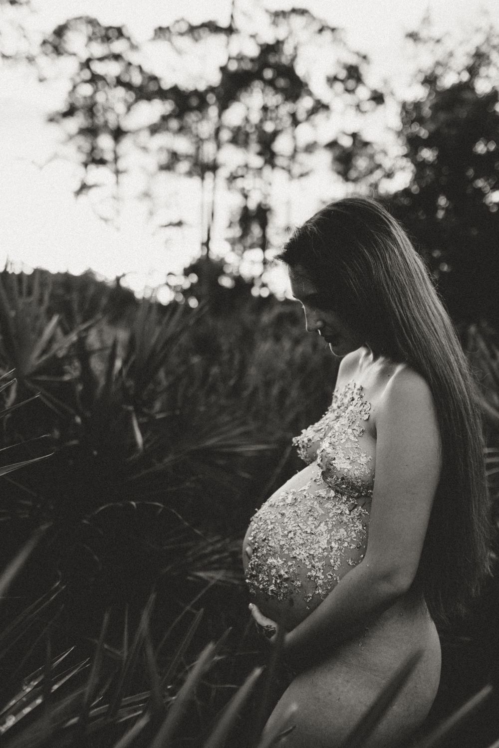 Black and white maternity photograph showing silhouette among tropical plants.