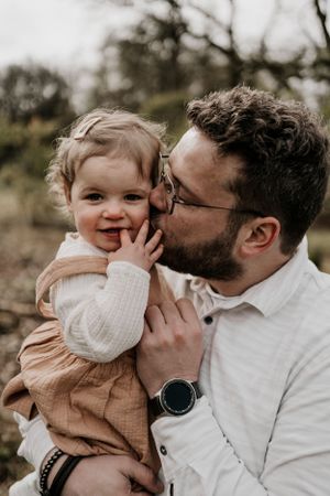Papa geeft dochter een kus op de wang tijdens een gezinsshoot