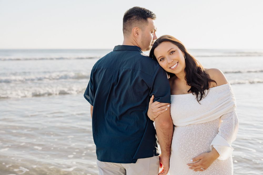 A couple shares a romantic moment together while walking along a sandy beach at sunset.