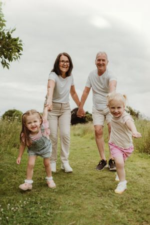 Family members playing and bending down together in a sunny outdoor field.