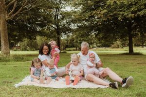 Family members relaxing together on a blanket in a park setting.