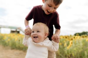 A joyful family plays together in a golden sunlit field of wildflowers during a summer afternoon.