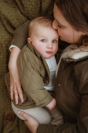 Intimate family moment captured in warm, moody lighting against textured background.