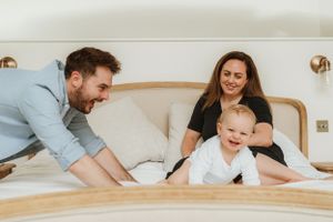 Family sharing intimate moments together on a white bed.