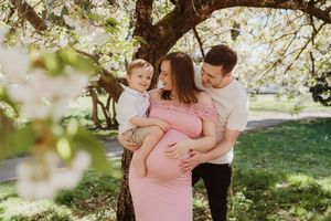 Family sharing tender moments under blooming spring trees in a sunlit park.