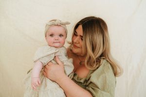 An intimate family portrait session against a neutral cream-colored background.