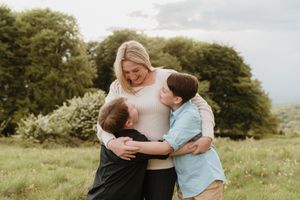 Sweet family cuddles and embraces in a sunny outdoor setting.
