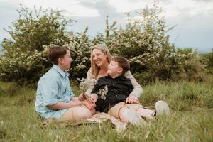 Family enjoying a tender moment together while relaxing in a grassy field.